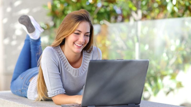 22638570 - beautiful woman on line browsing social media with a laptop outdoor in a park